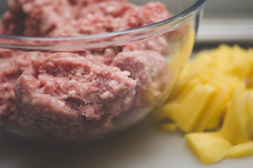 Sliced potato for soup and meat stuffing for making meatballs. Soup with meatballs and pasta prepear in process.
