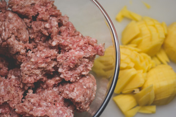 Sliced potato for soup and meat stuffing for making meatballs. Soup with meatballs and pasta prepear in process.