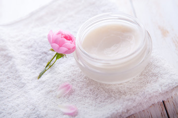 organic cosmetic with rose and pot of moisturizing face cream on white background top view