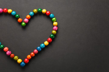 Colorful wooden beads in the form of heart isolated on black background for design. Saint Valentine's Day card on fabruary 14, holiday concept. Copy space for advertisement.