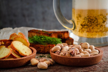 Beer in a glass, pistachios, rye croutons and crackers on a wooden table