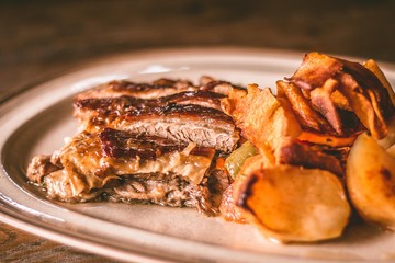 Closeup of a meat meal with potatoes on a rustic plate