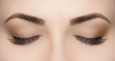 Beautiful Woman with long lashes in a beauty salon. Eyelash extension procedure.