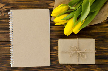 yellow tulips, notepad,  gift box on wooden table