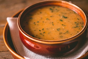 Closeup of a warm vegetable soup on wooden table and ceramic bowl