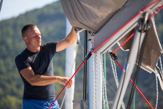 A young male sailor setting sail on his yacht.