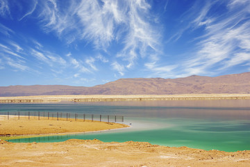 Turquoise water of the Dead Sea, Israel. Between the sea and dry mountains of red sandstone highway passes. 