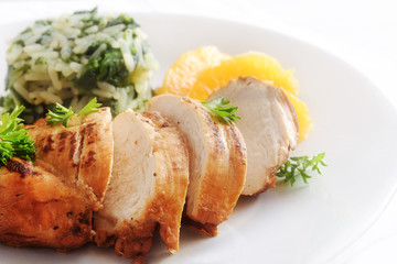 Chicken breast with orange fillets and spinach rice on a white plate, close up, copy space, selective focus, narrow depth of field