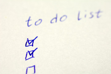 to do list on a white sheet of paper, pen notes completed check box. self management concept, close up, selective focus