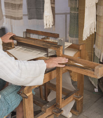 Hands of a man weaving on a loom