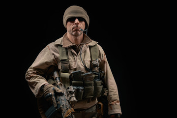 special forces soldier of the united states poses with a rifle on a black background