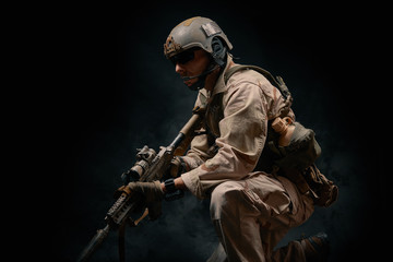 special forces soldier of the united states poses with a rifle on a black background