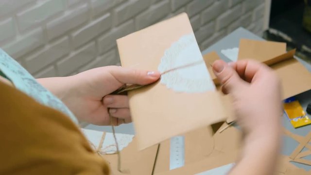 Professional woman decorator, designer working with kraft paper and wrapping envelope at workshop, studio. Decorating, handmade and art concept