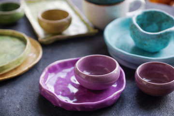 Homemade rustic crockery, colorful plates and bowls on dark stone concrete background