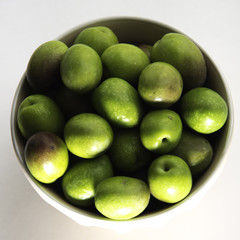 Green olives ready to eat in white background.