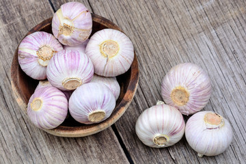 Heap of fresh garlic in a bowl on wooden table