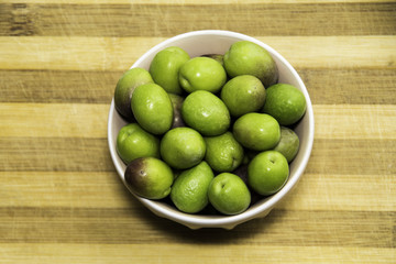 Plate of Green olives ready to eat in chopping board background.