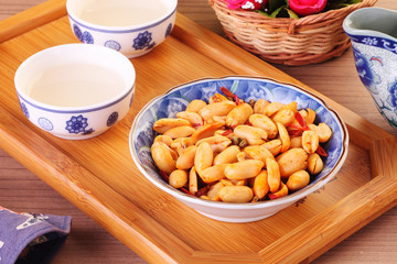 Spicy coated peanuts with tea on the table    