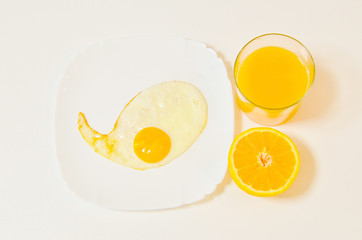 fried eggs with fresh orange juice on the white table