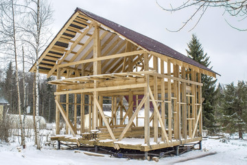 Frame wooden house in the background of snow. Preservation of a frame house for the winter. Construction of a house on a pile foundation.