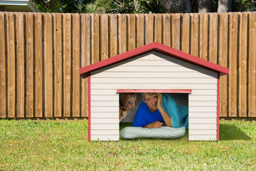 Husband or boyfriend man sleeping in the doghouse because of domestic problems with his wife or girlfriend like fighting, cheating infidelity, too much partying with the boys, won’t help with chores.