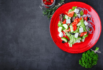 Greek salad feta, cherry tomatoes, olives, cucumbers on a dark background. Top view. Food background