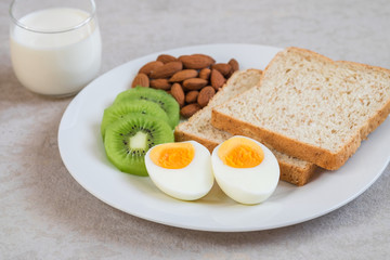 Boiled egg, whole wheat bread, kiwi, almonds and milk , Healthy food .