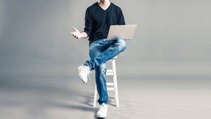 パソコンを持って椅子に座っているカジュアルな服装の男性
