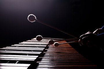 The hands of a musician playing the marimba in dark tones - obrazy, fototapety, plakaty