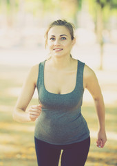Fototapeta premium happy female in sportwear running in the sunny park