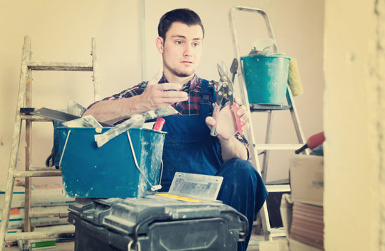 Young professional builder handyman choosing tool in toolbox