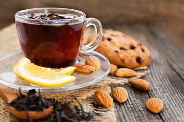 Tea in a cup with lemon and nuts on a wooden surface