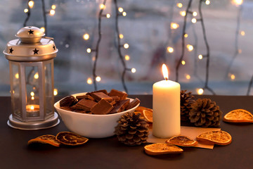 Christmas lantern with candle and chocolate on table. Holiday, New Year, Christmas, cosiness concept. Vintage style.