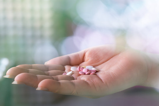 Pills on woman hand.Close up of woman hand holding lot of pills with bokeh and blur background.