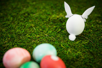 Figur Osterhase und bunte Ostereier auf grüner Wiese