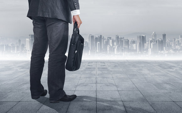 Businessman standing with back and looking for business. Cityscape background.