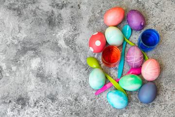 Flatlay f&uuml;r Ostereier f&auml;rben, bunte Eier, L&ouml;ffel und Farbe auf grauem Tisch