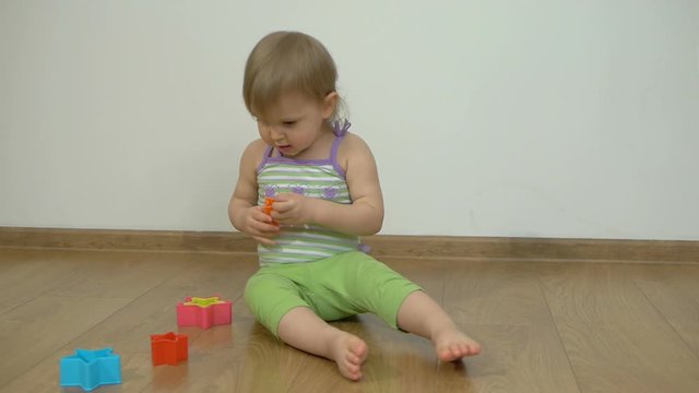 Little girl sitting on the floor playing with forms for baking cookies
