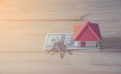 Business Real Estate Concept, House model with a key and dollar bills put on paper graph on wooden background.