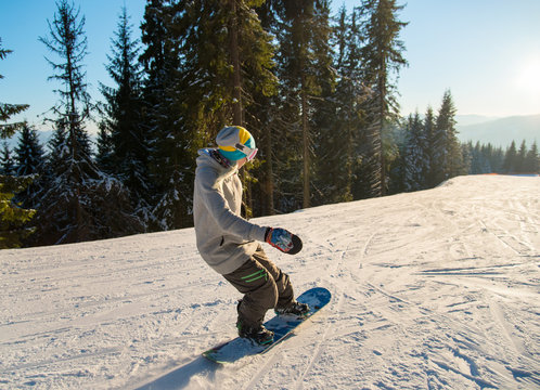 Young female snowboarder enjoying skiing on the mountain slopes on a sunny winter day at ski resort Bukovel