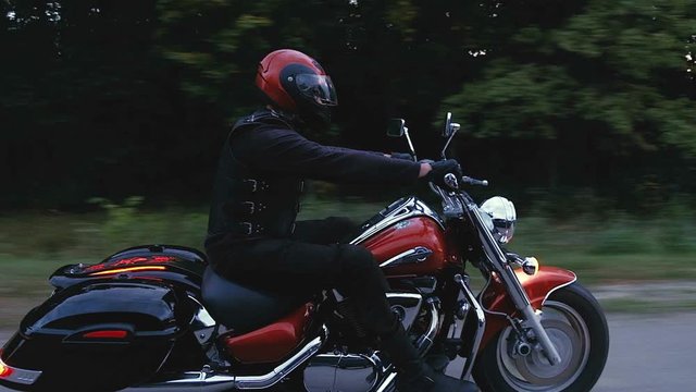 A man rides a motorcycle down a road in forest