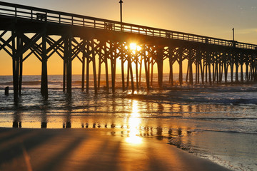 Golden sunrise over Atlantic ocean.Beautiful morning landscape with sun rising over ocean and wooden pier. Travel america background, tropical vacation concept. Myrtle Beach area, South Carolina, USA.