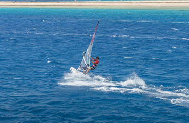 windsurfer on a board under a sail against the background of the sea, wind and waves.
