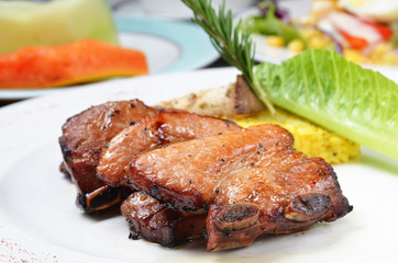 Closeup of barbecued pork ribs on white plate 