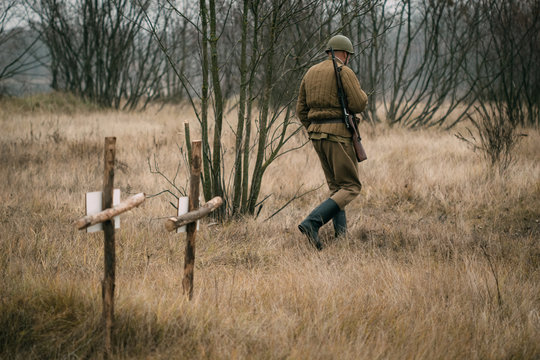 A soldier of the Red Army walks past graves