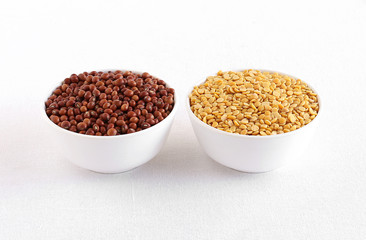 Pigeon pea in the left bowl and split pigeon pea, or toor dal, a traditional and popular Indian lentil, in the right bowl.