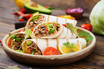 Burritos wraps with beef and vegetables on a wooden background. Beef burrito , mexican food. Healthy food background. Mexican cuisine. - obrazy, fototapety, plakaty