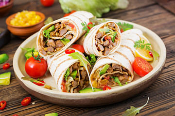 Burritos wraps with beef and vegetables on a wooden background. Beef burrito , mexican food. Healthy food background. Mexican cuisine.