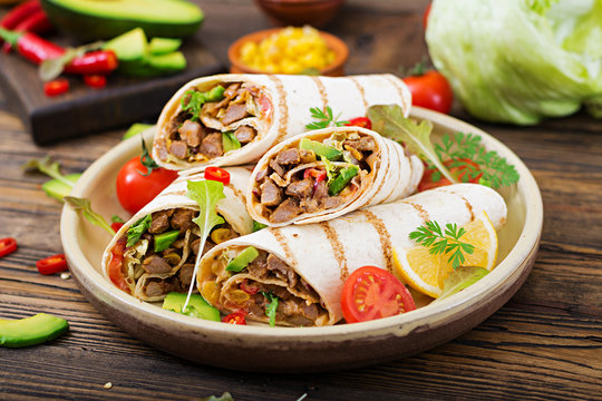 Burritos wraps with beef and vegetables on a wooden background. Beef burrito , mexican food. Healthy food background. Mexican cuisine.