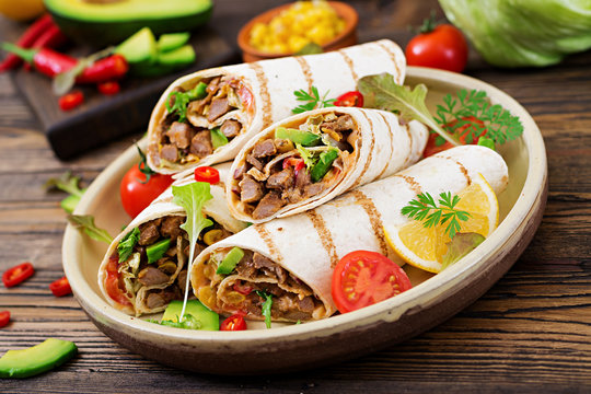 Burritos wraps with beef and vegetables on a wooden background. Beef burrito , mexican food. Healthy food background. Mexican cuisine.
